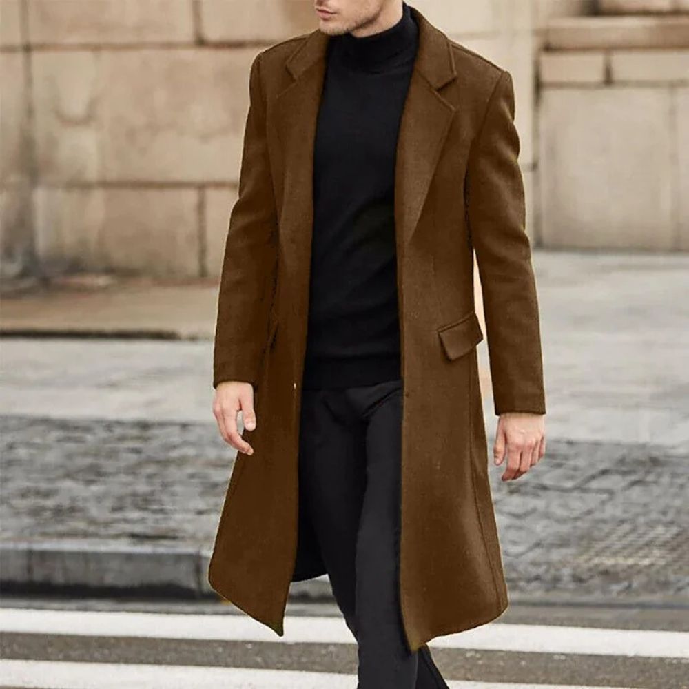 Hombre vistiendo un elegante abrigo largo de invierno, ideal para días de otoño e invierno.